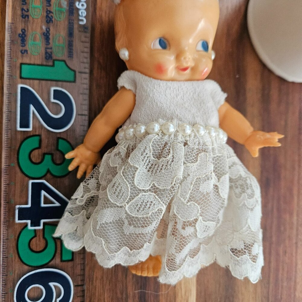 irwin kewpie doll in white dress with hat    part of middle finger broke